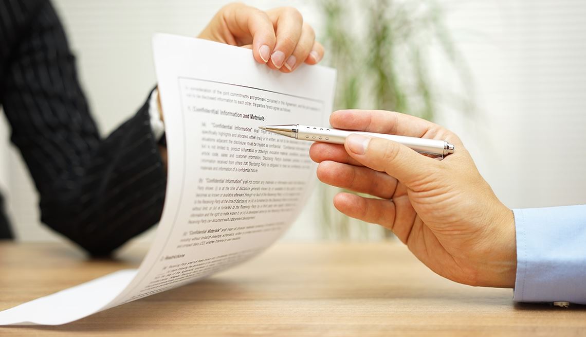 Person pointing a pen pointing at paper